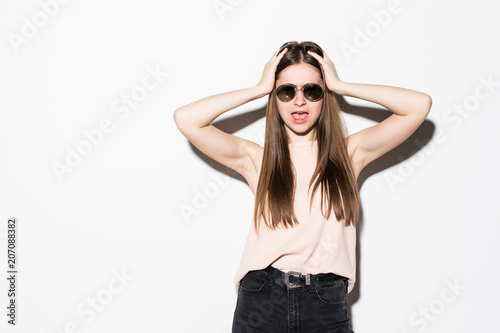 Young woman screaming with hands on her head, mouth wide open looking in panic at the camera isolated