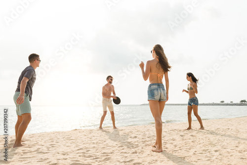 Group of friends playing at the beach in summer