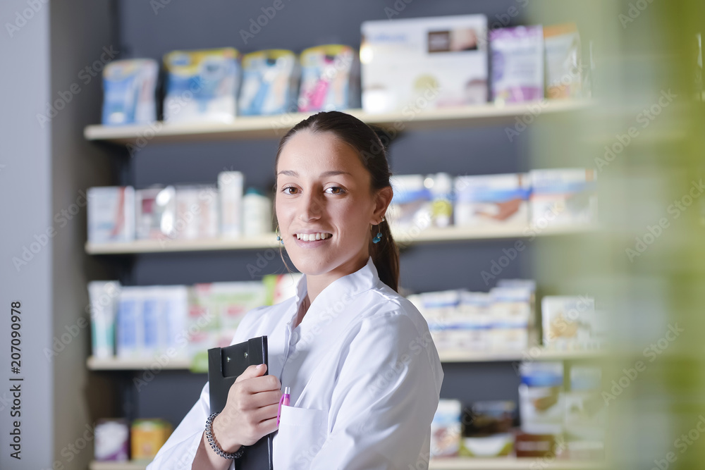 Beautiful pharmacist using notepad at the pharmacy Beautiful pharmacist using notepad at the pharmacy