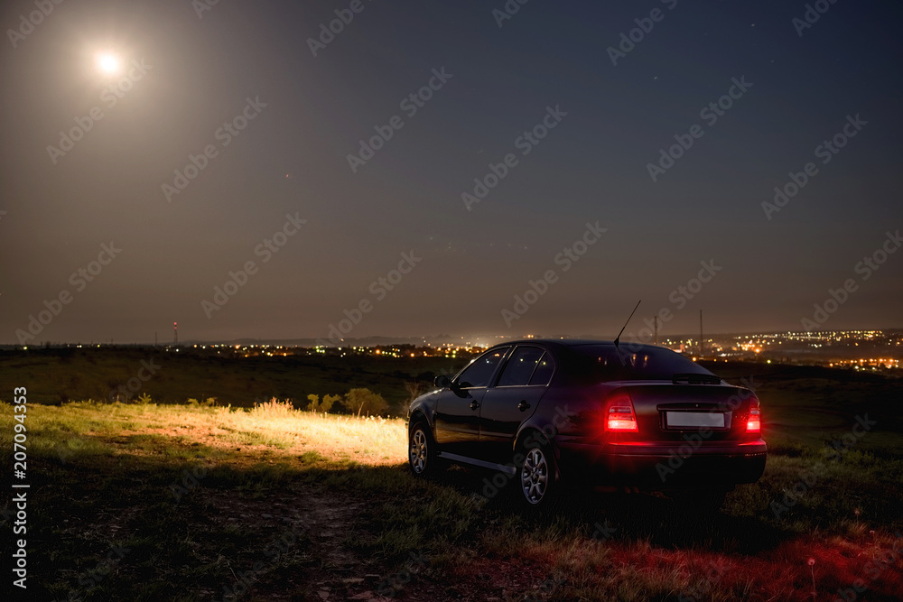 Black car in the field at night