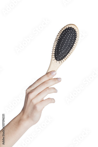 Female hand holding a hairbrush on isolated background © jandruk