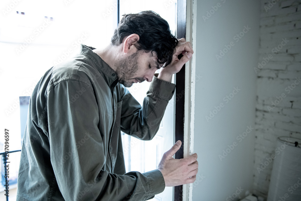 Fototapeta premium depressed man looking out a window at home in mental health concept