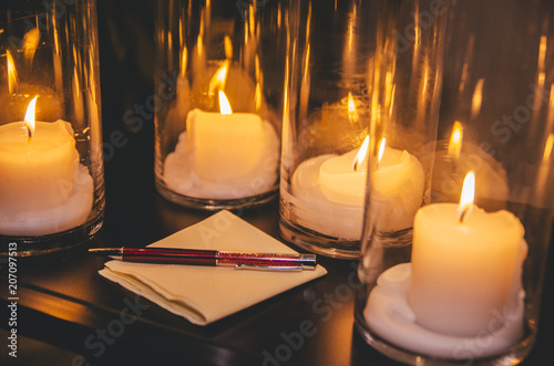 Pen siting on napkin on the black table luminated by the candles. photo