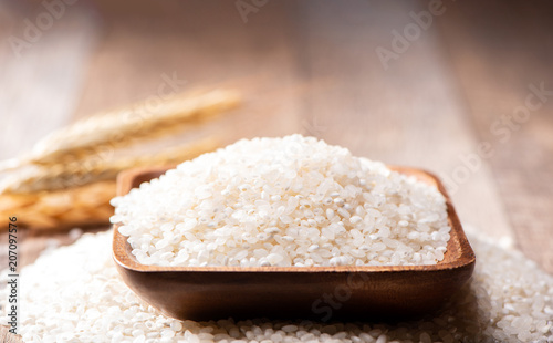 raw rice in a wooden bowl on wooden background