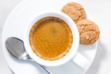 cup of espresso and almond cookies on a white table, closeup top view