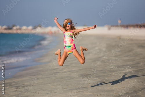 Happy child jumping in summer vacation on exotic tropical beach. Holiday on ocean coast for family with young children. Kids play at the sea.