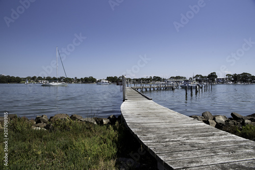 Wooden Pier that leads out into waterways with a boat photo