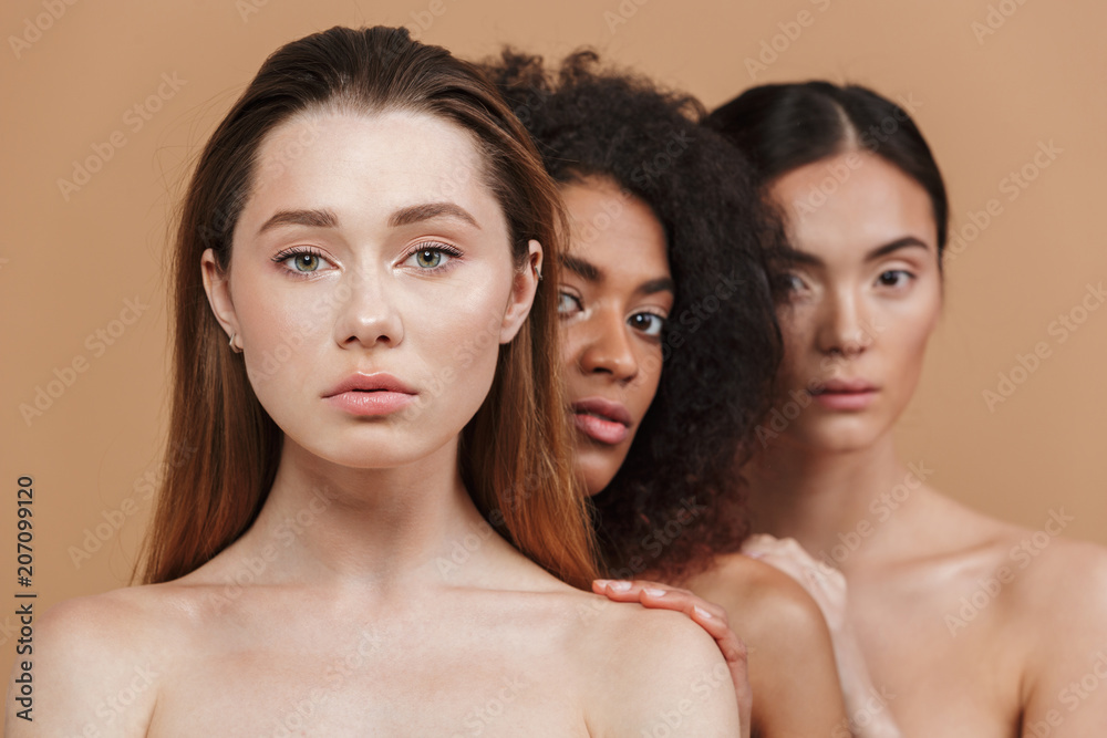 Beauty portrait of three nude women of different nation: caucasian, african  american and asian girls, standing together isolated over beige background  Stock Photo