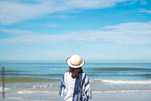 traveler young woman in casual dress with hat stand alone on beach has blue sky and sea background