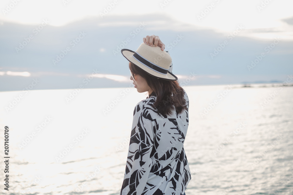 traveler young woman in casual dress with hat stand alone on beach has sea background