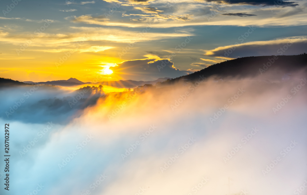 Dawn on plateau in morning with colorful sky, while sun rising from horizon shines down to small village covered with fog shrouded  landscape so beautiful idyllic countryside Dalat plateau, Vietnam
