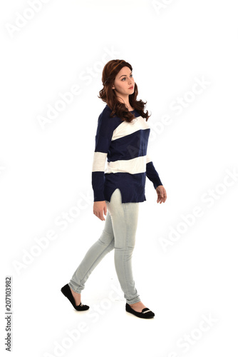 full length portrait of girl wearing striped blue and white jumper and jeans. standing pose on white studio background