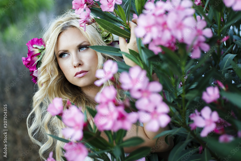 Fototapeta premium Romantic portrait of beautiful young blond woman surrounded by pink flowers