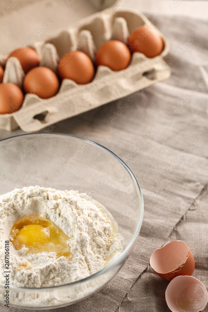 preparation of dough for flat bread. broken egg and flour in a glass bowl preparation of dough for flat bread. broken egg and flour in a glass bowl