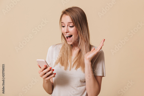 Portrait of a shocked casual girl looking at mobile phone