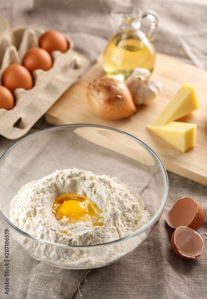 preparation of dough for flat bread. broken egg and flour in a glass bowl. flat bread with onion, cheese and garlic preparation of dough for flat bread. broken egg and flour in a glass bowl. flat bread with onion, cheese and garlic
