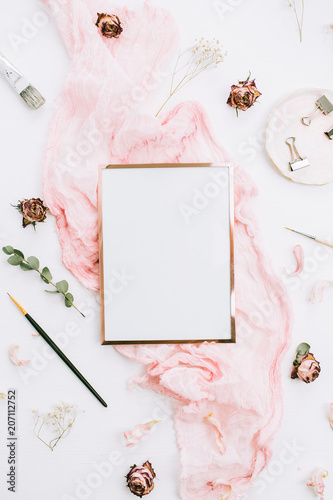 Photo frame with copy space on pink blanket with eucalyptus branches and rose flowers on white background. Flat lay, top view still life artist concept.