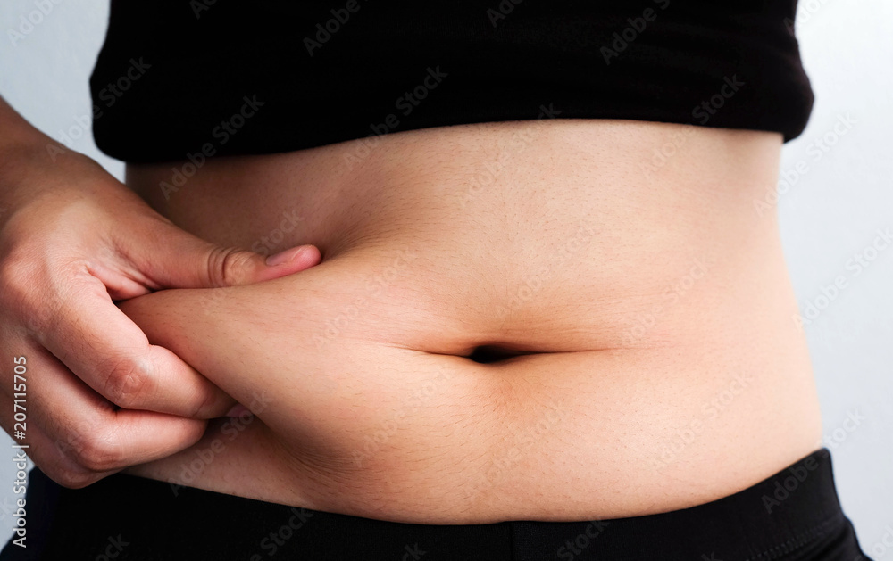 woman hand catching fat body belly paunch , diabetic risk factor . woman hand catching fat body belly paunch , diabetic risk factor .