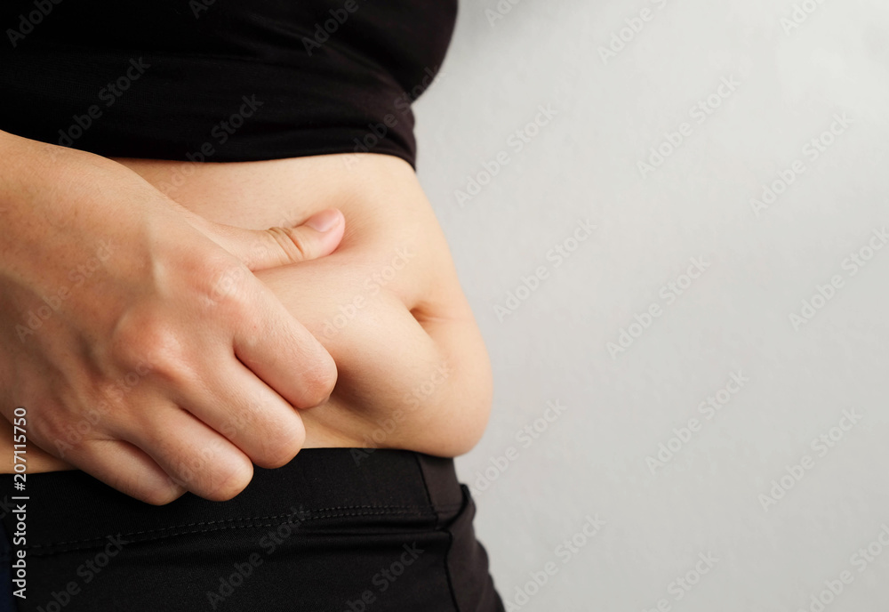 Side of woman hand catching fat body belly paunch , diabetic risk factor . Side of woman hand catching fat body belly paunch , diabetic risk factor .