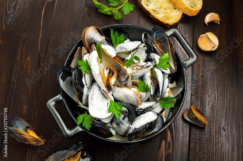 Mussels in a white wine and cream sauce on a table. Classic French meal Moules marinière. photo