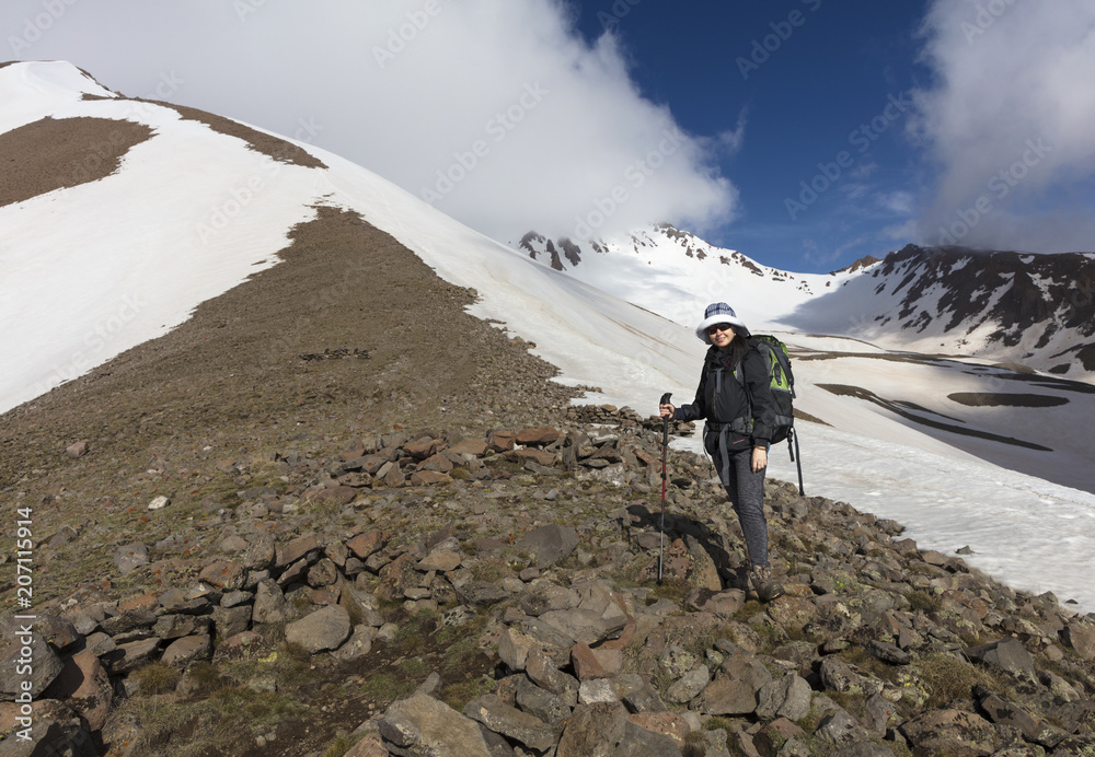 The tourist rises up the mountainside to the snow-capped summit