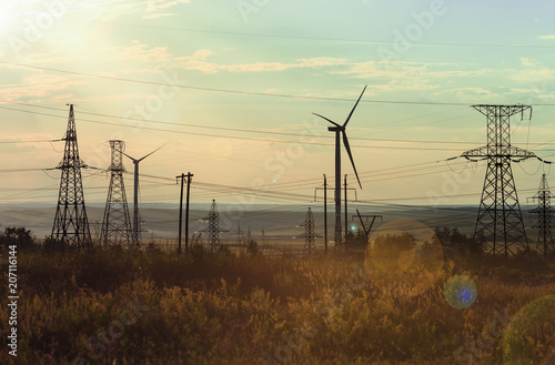 Wind-driven generators (wind generators), support of high-voltage power lines, wires, against the background of the sunshine sky