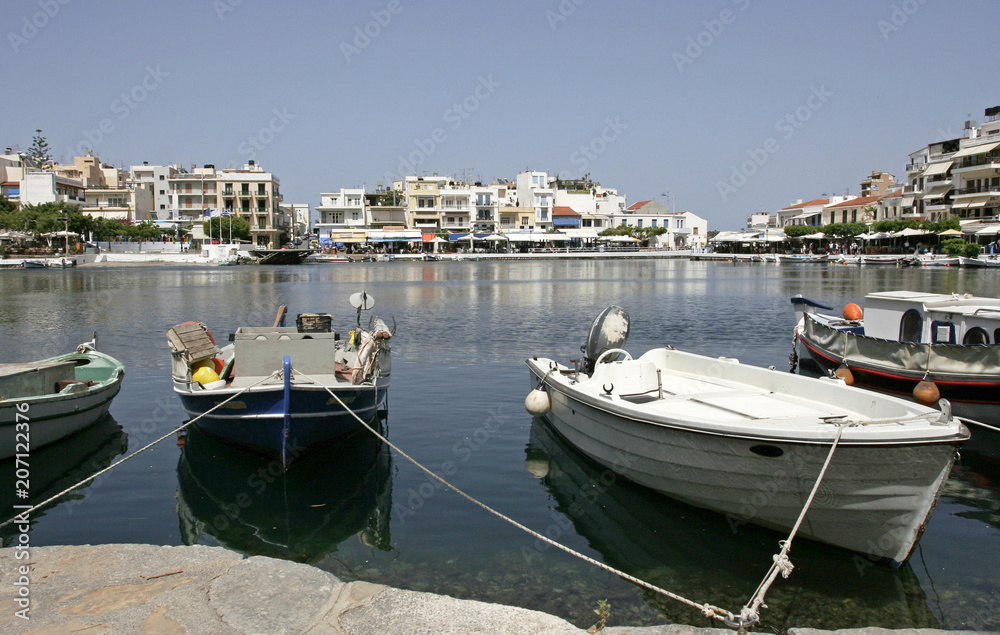 The white boats on the coast of the lake and white houses and cafes in the small mediterranean town on the sunny day