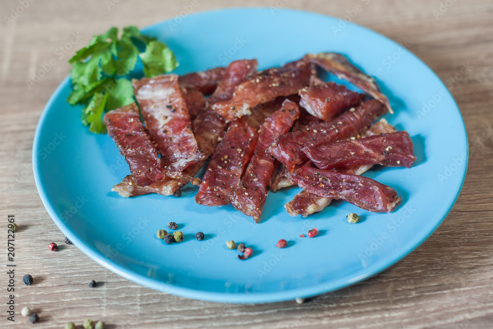 pieces of meat snacks with spices on a blue plate