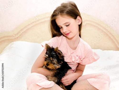 Adorable little girl child holding and playing with puppy yorkshire terrier