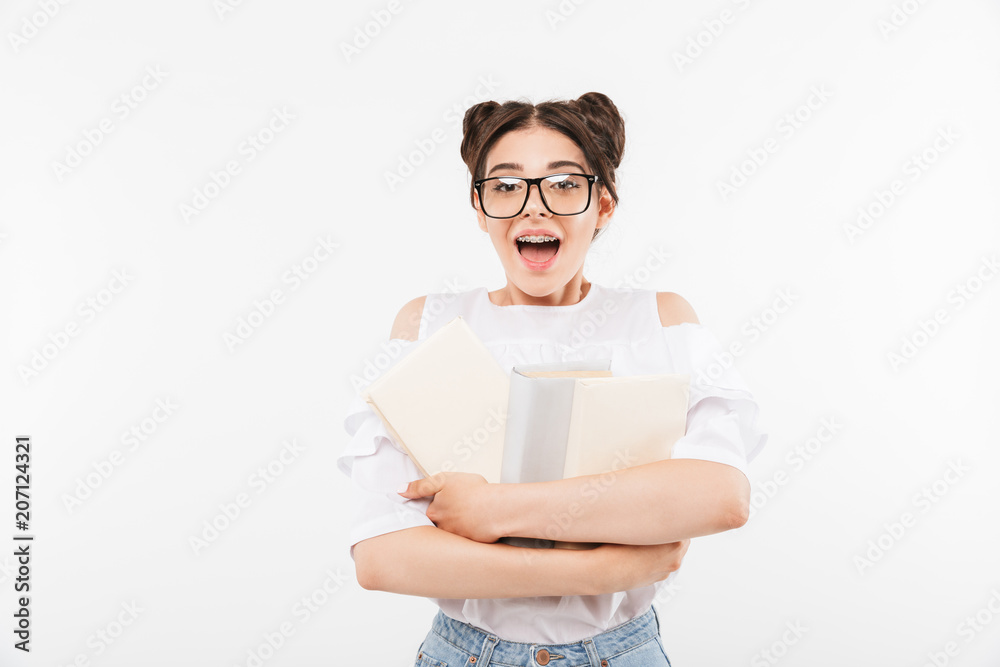 Young happy female student or school girl with double buns hairstyle and dental braces smiling and holding many studying books, isolated over white background Young happy female student or school girl with double buns hairstyle and dental braces smiling and holding many studying books, isolated over white background