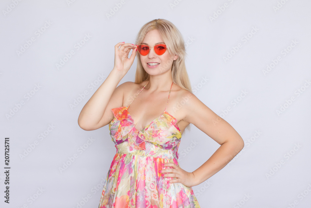 portrait of a young blond woman with long hair in a floral pink dress, and bright pink sunglasses portrait of a young blond woman with long hair in a floral pink dress, and bright pink sunglasses