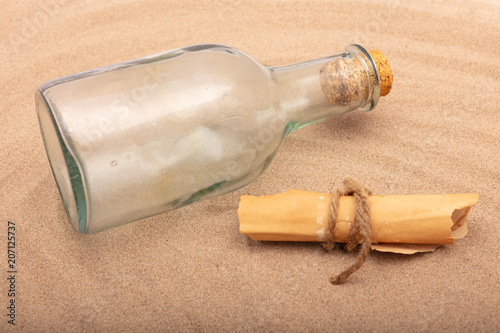 Wrapped message beside an old bottle on the sand of a beach