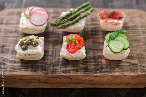 Set of different mini sandwiches on a wooden board.