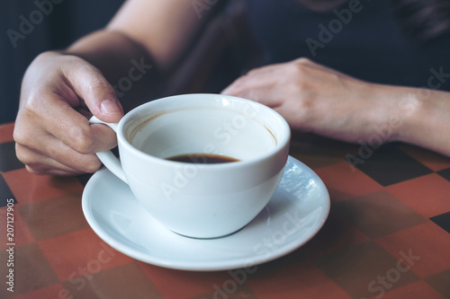 Closeup image of a hand holding and drinking hot coffee in cafe