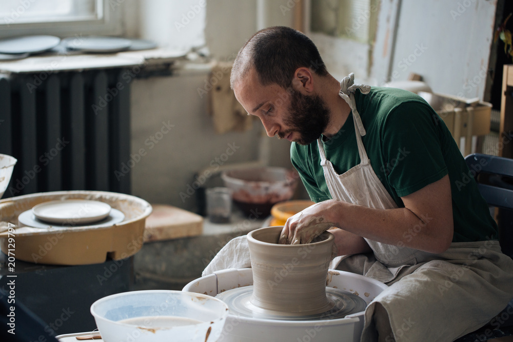 Handcrafted on a potter's wheel,Hands make clay from various items for home and sale in the store and at the exhibition, ceramic items are made in hand, stylish bearded young man makes products Handcrafted on a potter's wheel,Hands make clay from various items for home and sale in the store and at the exhibition, ceramic items are made in hand, stylish bearded young man makes products