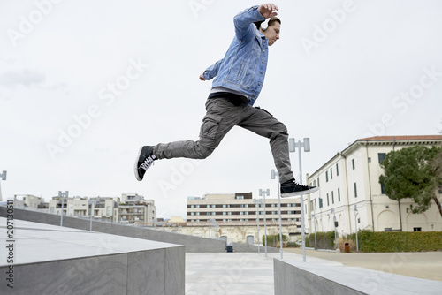 Young man jumping over gap between walls, mid air