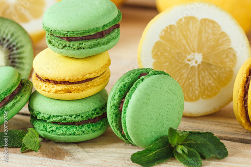 Green and yellow french macarons with kiwi, lemon and mint decorations