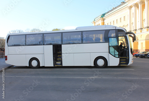 White Modern Tourist Coach Bus on Parking Lot of City Street. Simple Empty Bus on Asphalt Road on Summer Day. Travel and Tourism Concept, Regular Transportation for Tourists on Sightseeing Tour.