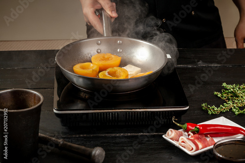 Peaches on a fry pan. Canned fruit yellow peaches, black wooden background, board. photo
