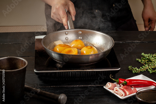 Peaches on a fry pan. Canned fruit yellow peaches, black wooden background, board. photo