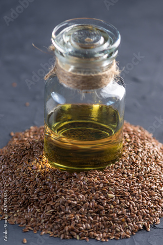 Flax seeds in a pile and linseed golden oil in a glass bottle on a dark background. Diet with omega 3 fatty acids.