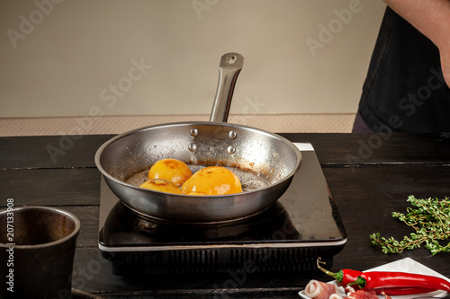 Peaches on a fry pan. Canned fruit yellow peaches, black wooden background, board. photo