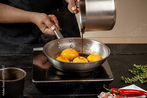 Peaches on a fry pan. Canned fruit yellow peaches, black wooden background, board. photo