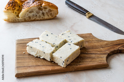 Turkish Feta Cheese with Black Cumin (Sesame) Seeds on Wooden Surface with Knife. photo