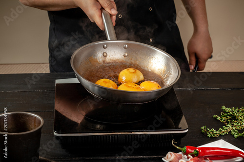 Peaches on a fry pan. Canned fruit yellow peaches, black wooden background, board. photo
