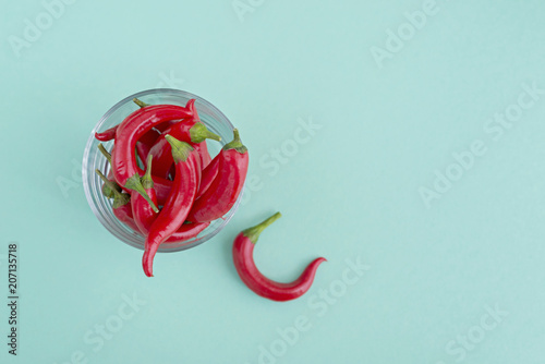 Red hot chili pepper in glass bowl on green background photo