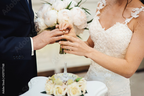 Hands of groom and bride at wedding day. Bridal couple hugging. Wedding bouquet at background. Wedding love and family concept close up macro photo with selective focus photo