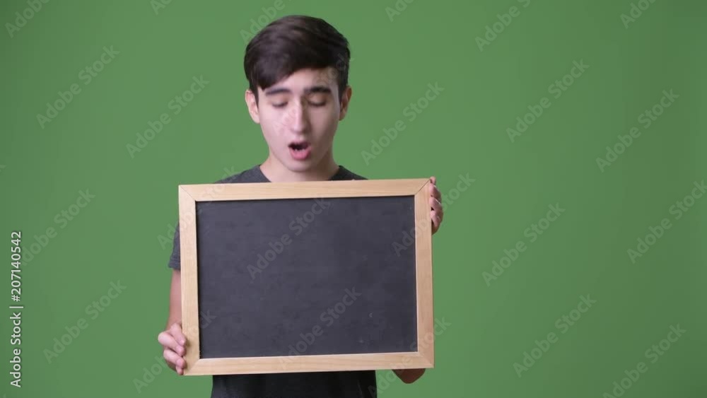 Young handsome Iranian teenage boy against green background Young handsome Iranian teenage boy against green background