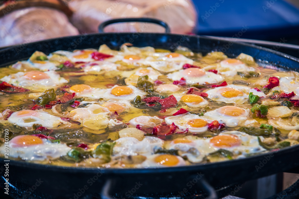 Traditional spanish big pan of fried eggs, paprika, dried tomatoes and parsley. Selective focus.3