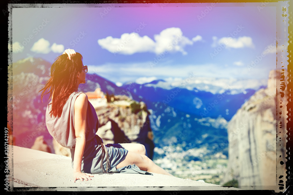 photo of the beautiful young woman sitting on the stone railing and looking at the splendid view in Greece. Image with film old frame.